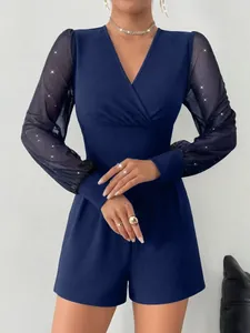 Nahaufnahme eines marineblauen Jumpsuits mit V-Ausschnitt und glitzernden Netzärmeln