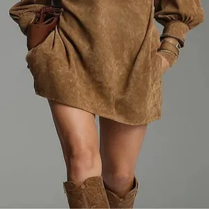 Detailopname van een bruine vintage suède jurk met lange mouwen en strakke manchetten