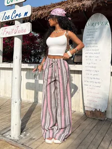 Lifestyle view of striped drawstring wide-leg pants in a tropical beach setting