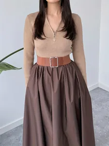 Detail of French style ribbed knit top and brown pleated skirt with wide waist belt