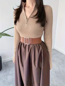 Detail shot of an elegant beige ribbed knit top paired with a stylish wide brown buckled belt