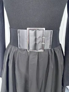 Detail of a wide black elastic belt with a silver buckle on a black dress