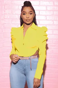 Detail view of yellow long sleeve blouse with puff shoulders and waist cutout design.