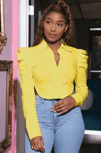 Detail of yellow long sleeve shirt with puff shoulders and side waist cutout design.