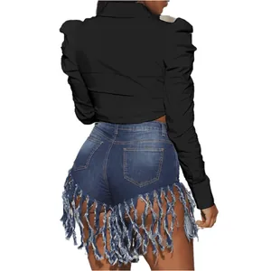 Back view showing black puff shoulder cropped top paired with fringed denim shorts