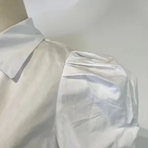 Close-up detail of pleated puff shoulder on a white lapel long sleeve shirt for women