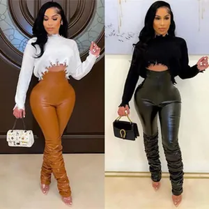 Detail of fashion two-piece set with cropped sweater and high waist stacked leather pants