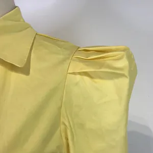 Close-up detail of a yellow long sleeve blouse featuring pleated puff shoulder design.