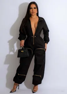 Detail showing utility pocket with gold zipper on a black waist-cinching cargo jumpsuit