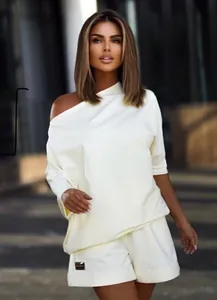 Close-up view of a stylish white off-the-shoulder loose sweatshirt and shorts two-piece set.