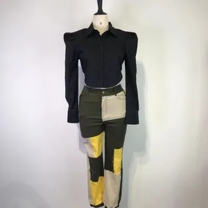 Detail view of women's black puff sleeve crop shirt with green patchwork trousers