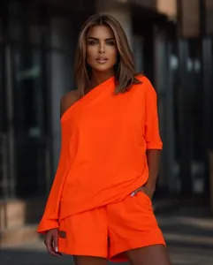 Model wearing a vibrant neon orange off-shoulder sweatshirt and matching shorts set.