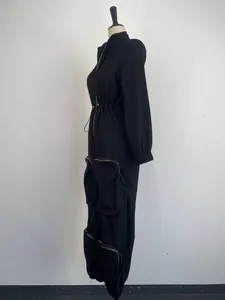 Side view detail of a black cargo jumpsuit with metal zippers and cinched waist