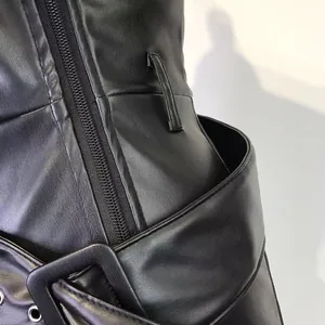 Macro detail view of black high-waist PU leather pants with metal buckle and zipper