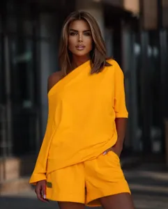 Detail of bright yellow one-shoulder sweatshirt and shorts set worn by a model