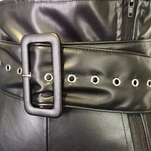Detail view of high-waisted black PU leather pants with wide belt and buckle
