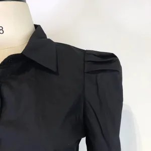 Close-up detail of the elegant pleated puff sleeve on a black fashionable lapel blouse for women