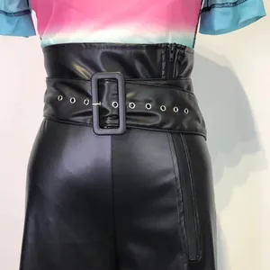 Close-up of high waisted black PU leather pants with a wide eyelet belt.