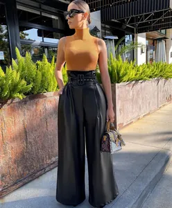 Close-up detail of high-waisted black PU leather wide-leg trousers with metal eyelet belt