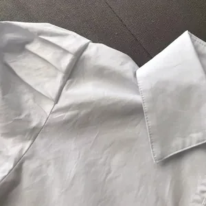 Detail shot of a white long-sleeved shirt featuring a classic lapel collar and shoulder structure
