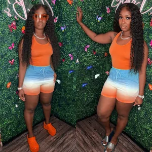 Full view of women's athletic set with orange racerback top and colorful gradient shorts
