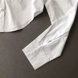 Close-up of white long sleeve shirt cuff showing three button details and fabric texture.