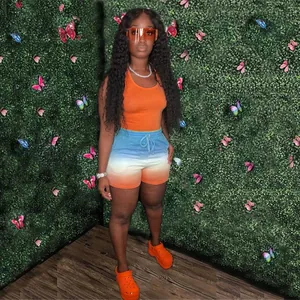 Close-up of a women's outfit with an orange tank top and blue gradient drawstring shorts.