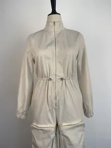 Front detail of a beige cargo jumpsuit with metal zippers and drawstring waist