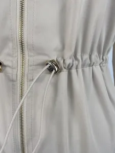 Close-up of adjustable drawstring waist detail on beige utility jumpsuit with metal toggle