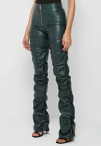 Detalle de pantalones de cuero PU verde oscuro con diseño único de pierna fruncida.