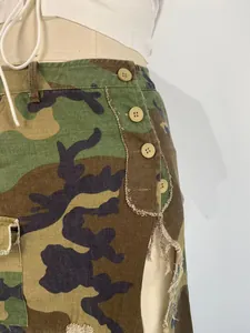 Close-up detail of a camouflage skirt with distressed edges and button accents