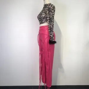 Zijaanzicht van roze PU-leren broek met vetersluiting en luipaard mesh top detail.