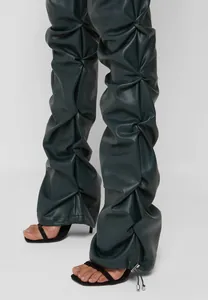 Primer plano de pantalones acampanados de cuero PU verde oscuro con detalle fruncido.
