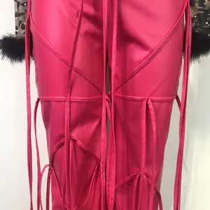 Gedetailleerde opname van een roze PU-leren broek met vetersluiting en unieke riempjes.