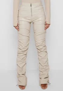 Vista frontal de elegantes pantalones ajustados de cuero PU beige fruncidos para mujer.