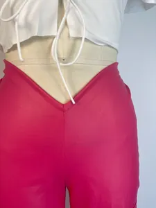 Detail shot of women's fuchsia PU leather trousers with unique V-shaped low waist design.
