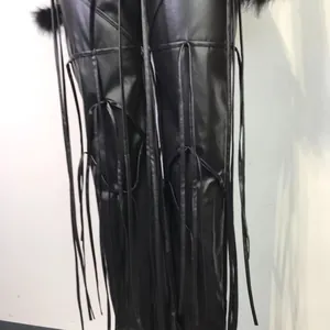 Detailopname van zwarte PU-lederen broek met modieuze lange kwastjes en bontrand.
