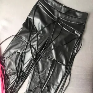 Detail van zwarte PU-lederen legging met een vetersluiting en een zachte textuur