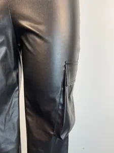 Close-up view of black PU leather cargo pants showing side pocket detail and material texture.