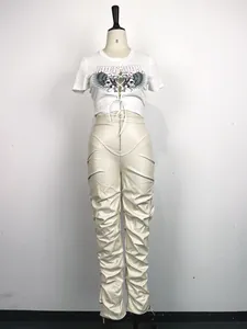 Detalle de pantalones de cuero PU plisados de cintura alta en color crema para mujer.