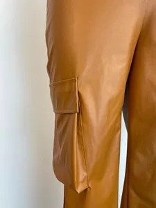 Detail shot of brown PU leather cargo pants showing side pocket and smooth texture