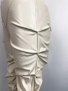 Detalle de los pliegues fruncidos en pantalones acampanados de cuero PU crema