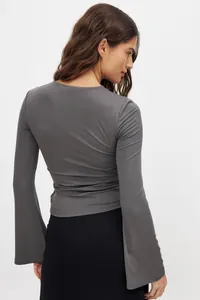 Vista trasera detallata de un top gris de manga larga con elegantes mangas de campana