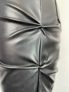 Vista detallada del diseño plisado de alta calidad en pantalones de cuero PU negro