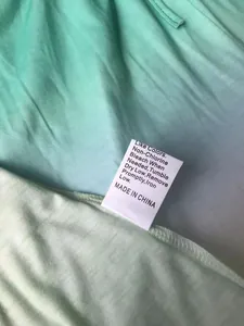 Close-up detail of clothing care label on mint green gradient fabric
