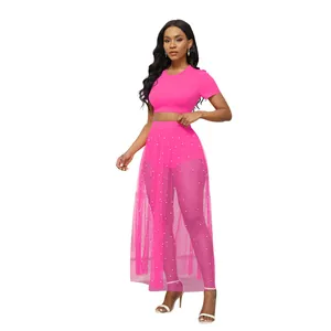 Set da spiaggia 3 pezzi con crop top rosa e gonna lunga in rete trasparente e perle.