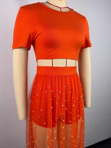 Completo da spiaggia arancione 3 pezzi con gonna in tulle perlato e crop top su manichino.