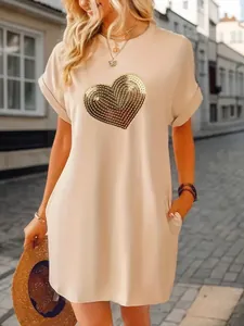 Detail view of women's beige T-shirt dress featuring a golden sequined heart design.