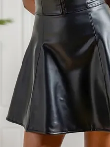 Gros plan d'une jupe en similicuir noir montrant la texture lisse et la coupe en ligne A.