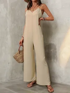 Model wearing a minimalist beige spaghetti strap wide-leg jumpsuit in a summer street style